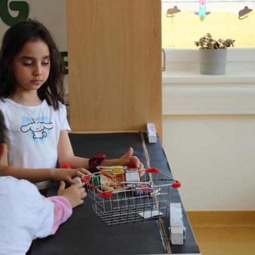 Mädchen steht am Fließband unseres Spielsupermarkts 