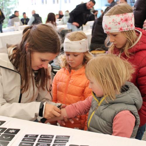 3 Kinder an der Tattoo Station mit einer Betreuerin 