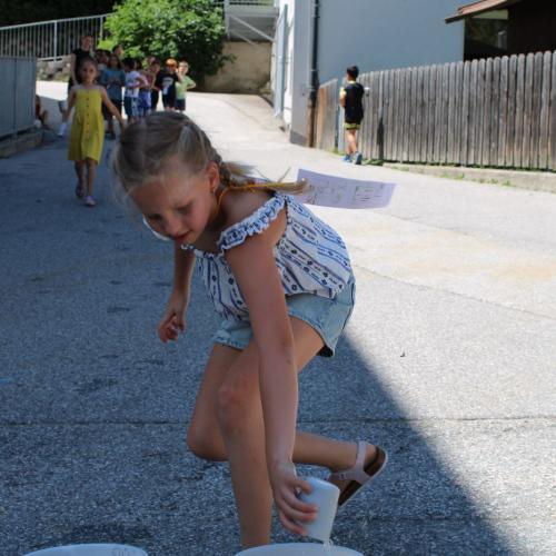 Mädchen leert Becher mit Wasser in einen Eimer 