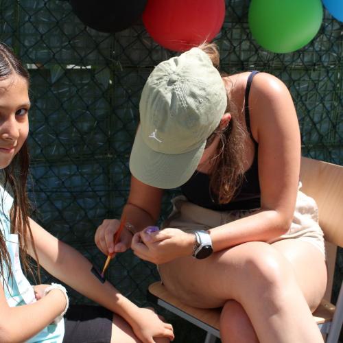 Mädchen schaut in die Kamera und bekommt ein Glitzertatto auf den Arm 
