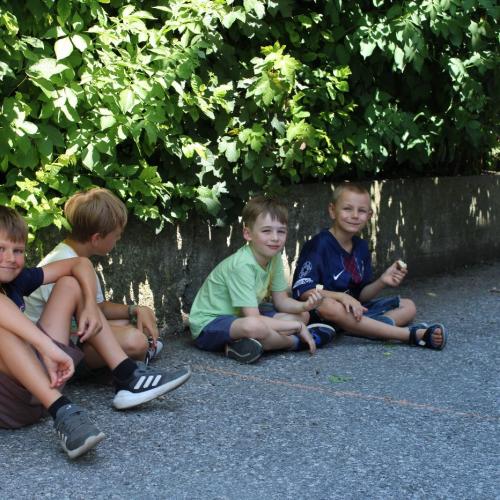 4 Jungen sitzen im Schatten am Boden 