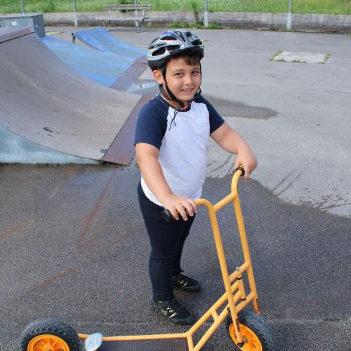 ein Junge fährt Roller und lächelt 