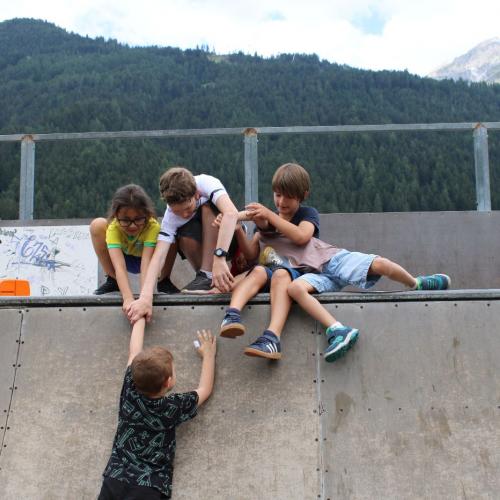 4 Kinder helfen einem anderen Kind auf der Rampe 