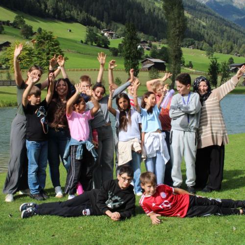 Gruppe mit Vielen Kindern und Betreuern stehen zusammen und Strecken die Arme in die Luft