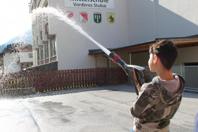 Kind spritzt mit Wasserschlauch