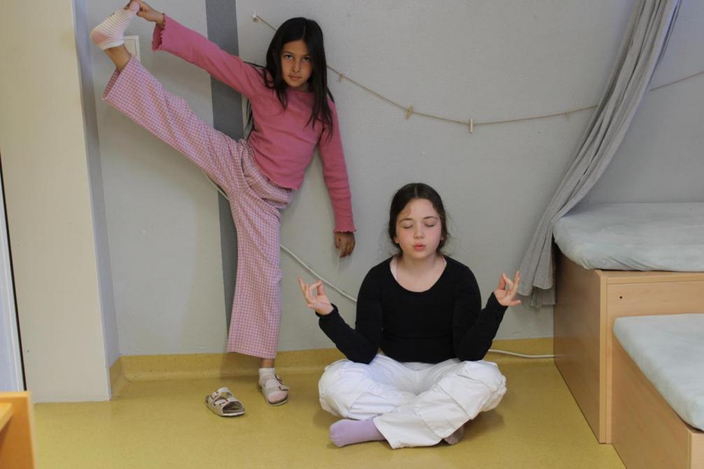 Zwei Kinder in sportlichen Posen (Dehnen und Yoga) 