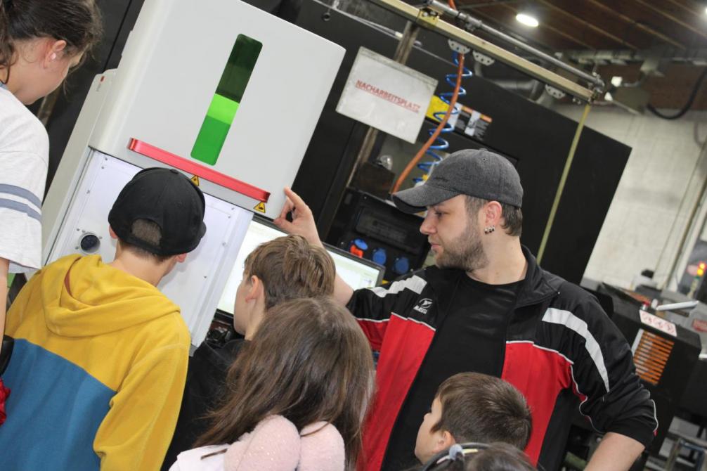 Mitarbeiter zeigt den Kindern die Arbeitsprozesse 