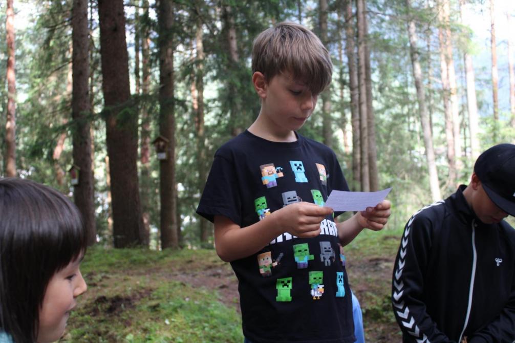 Kind liest im Wald etwas vor 
