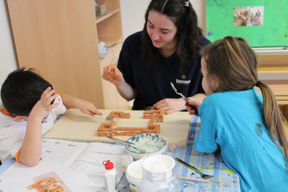 Kinder bauen eine Burg mit einer Betreuerin