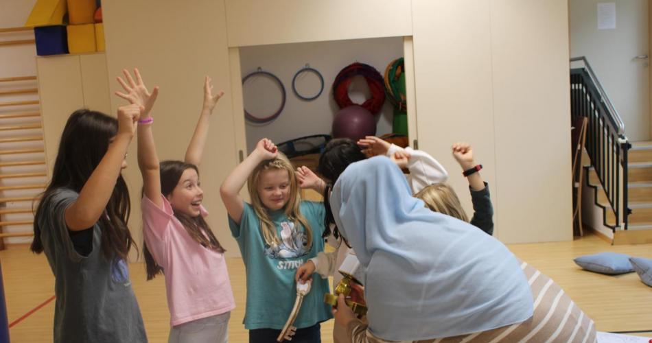 Kinder im Turnsaal, bekommen ein Spiel erklärt und freuen sich 