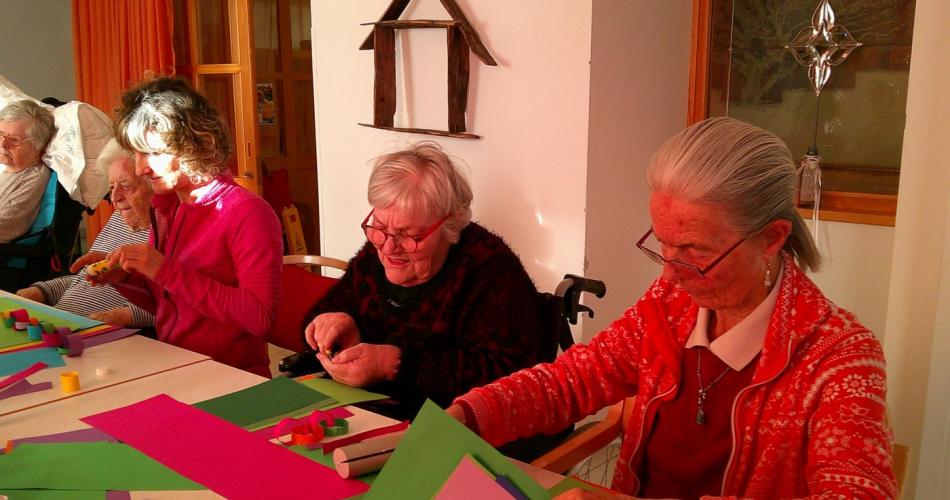 Es sind 4 Senioren beim Basteln zu sehen