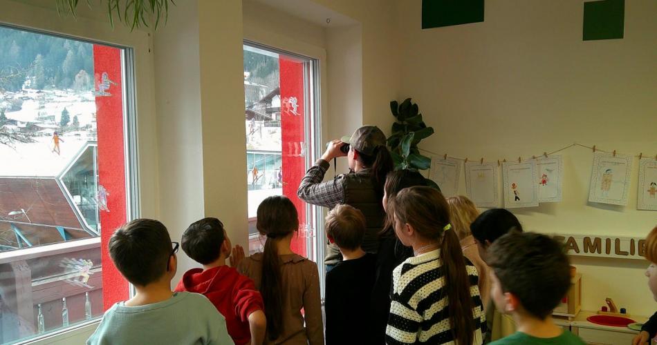 Kinder und Jägerin schauen durch ein Fernglas