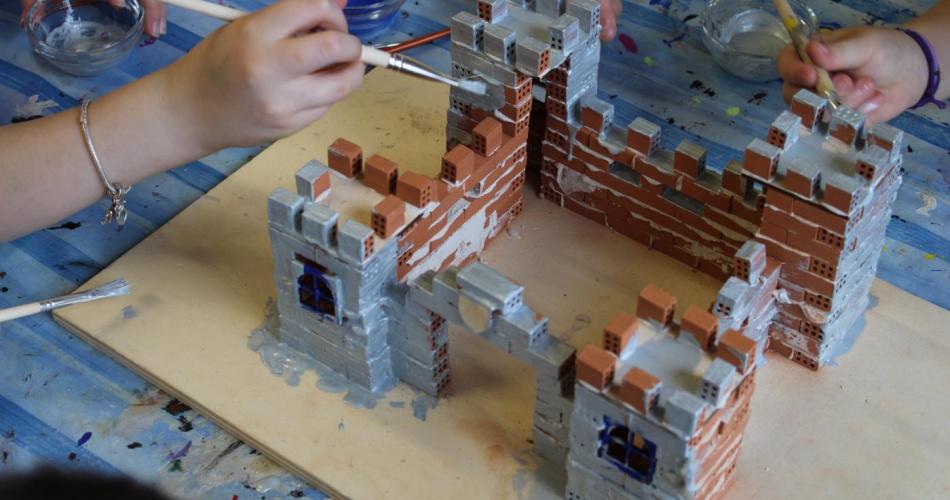 Kinderhände bemalen eine Burg 