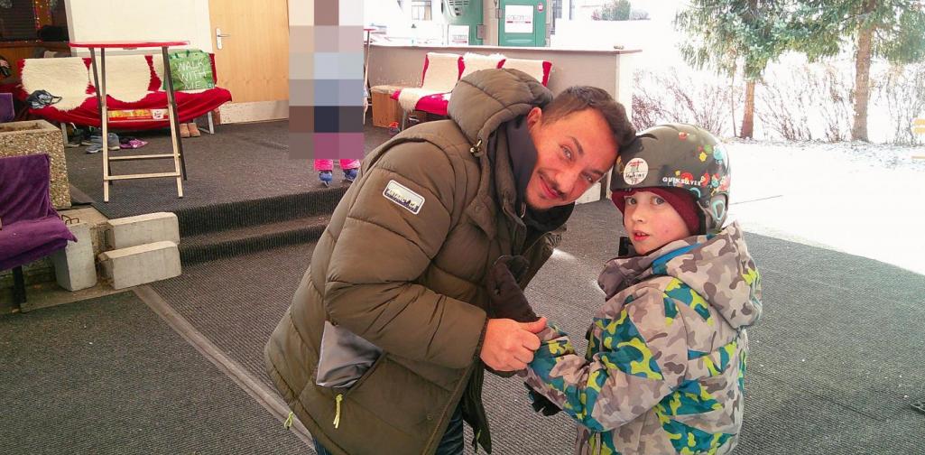 Betreuer hilft einem Kind sich die Handschuhe anzuziehen