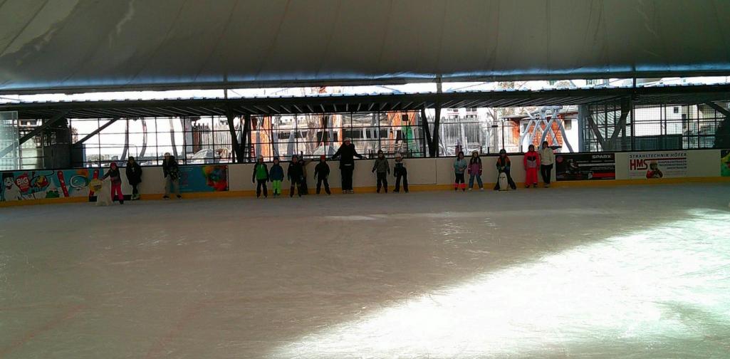 Viele Kinder spielen auf dem Eislaufplatz